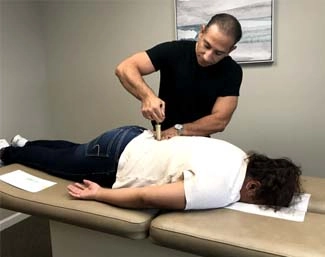 Chiropractor Milford CT Franco Menta Using Adjustment Tool On Patient